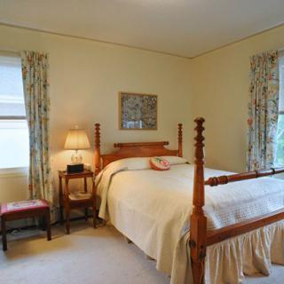 A cozy bedroom with traditional decor featuring a four-poster bed and warm lighting.