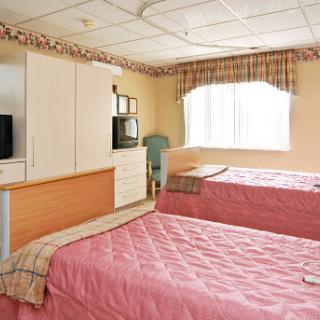 A cozy hotel room featuring two beds and a window with natural light.
