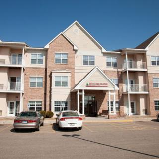 A multi-story residential building with parked cars in the front.