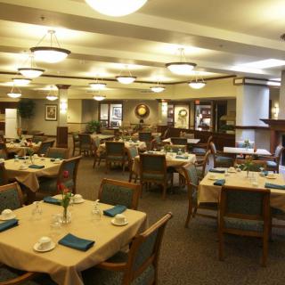 A spacious dining room with neatly arranged tables and chairs, featuring elegant lighting and decor.