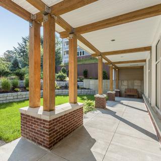 A spacious outdoor patio with wooden beams and a landscaped garden.