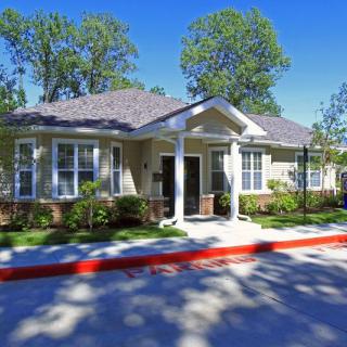A single-story suburban house with a neatly maintained front yard and trees in the background.