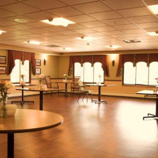A spacious dining area with neatly arranged tables and chairs, illuminated by warm lights.
