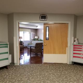A view of an interior space with a doorway leading to a waiting area, featuring comfortable seating and decorative elements.