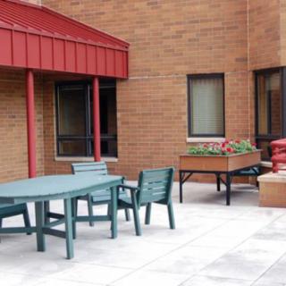 A patio area with green outdoor furniture and a brick building backdrop.