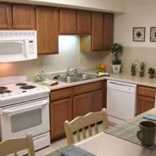 A cozy kitchen with wooden cabinets, featuring modern appliances and a dining area.