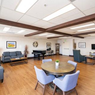 A spacious and bright lounge area featuring comfortable seating, a piano, and modern decor.
