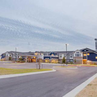 A suburban residential building complex with a wide road in the foreground.