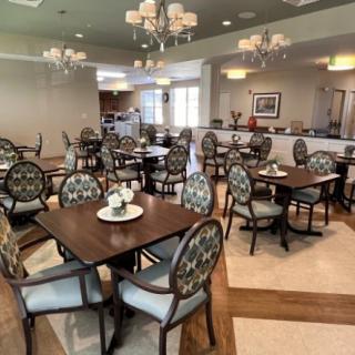 A well-arranged dining area with elegant tables and chairs, highlighted by chandeliers.