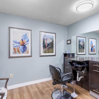 A modern hair salon interior featuring a styling station with a salon chair, large mirror, and wall artwork.