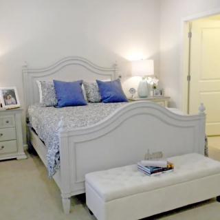 A cozy bedroom with a white bed, blue pillows, nightstands, and soft lighting.