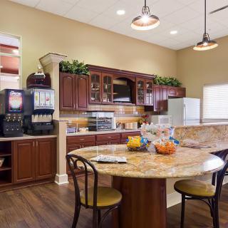 A well-furnished kitchen and dining area with wooden cabinets and a round table.