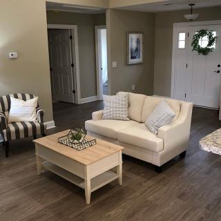 A cozy living room with a beige couch, striped chair, and wooden coffee table on a hardwood floor.