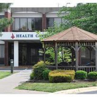 A health center building with a gazebo and landscaped garden at the entrance.
