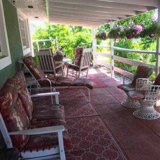 A cozy outdoor porch with various chairs and hanging plants, ideal for relaxation.