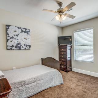A cozy bedroom with a single bed, ceiling fan, and natural light from the window.