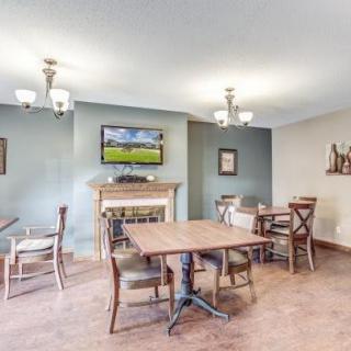 A cozy dining area with wooden tables and chairs, a fireplace, and a television mounted on the wall.