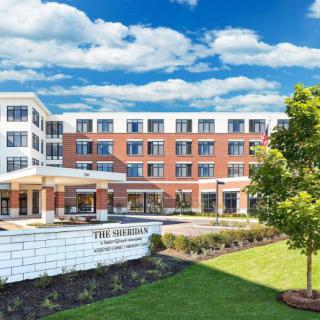 A modern residential building with well-maintained landscaping on a sunny day.