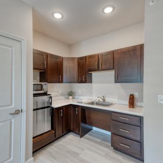 A modern apartment kitchen with dark wood cabinets and stainless steel appliances.