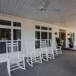 A cozy porch with white rocking chairs and potted plants.