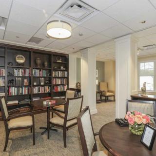 A cozy library room with bookshelves, tables, and chairs for reading.