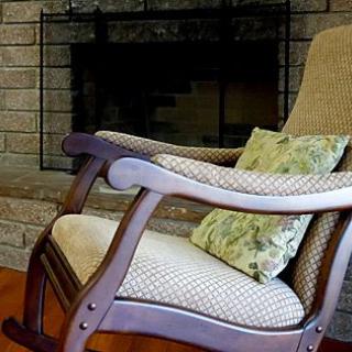 A cozy rocking chair with a patterned cushion placed in front of a brick fireplace.