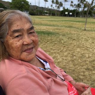 An elderly woman relaxing in a wheelchair at a park.