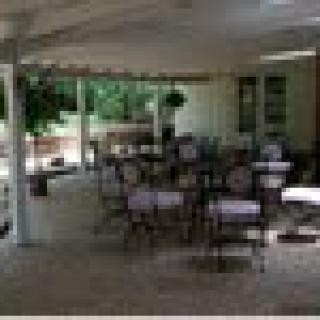 An outdoor patio area with tables and chairs under a covered structure.