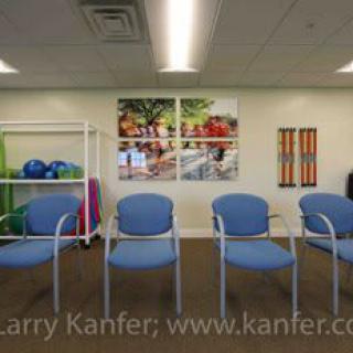 A modern waiting room with blue chairs and colorful artwork on the walls.