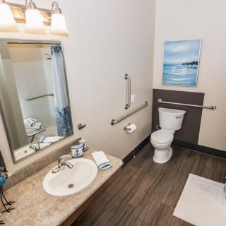 A clean and modern bathroom featuring a sink, toilet, mirror, and wall art.