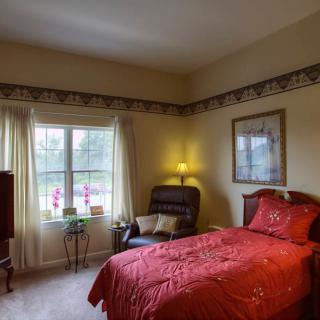 Cozy bedroom with a red bedspread, armchair, and large window.