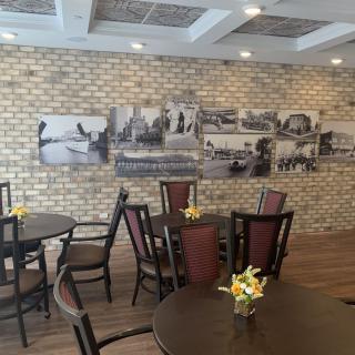 A cozy restaurant interior featuring brick walls, black and white artwork, and tables with floral centerpieces.