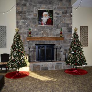 A beautifully decorated living room for the Christmas season, featuring two Christmas trees and a cozy fireplace.