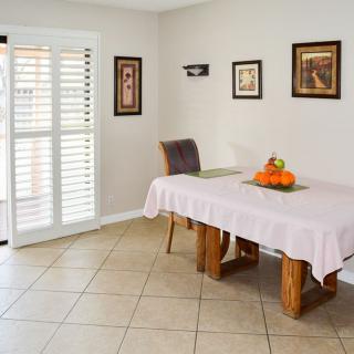 A cozy dining area with a table, chairs, and decorative elements including framed art and a fruit bowl.