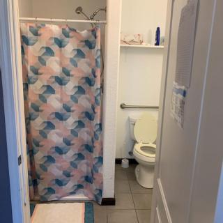 A small bathroom featuring a shower with a colorful curtain and a toilet.