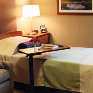 A cozy hospital room with a bed, side table, and warm lighting.