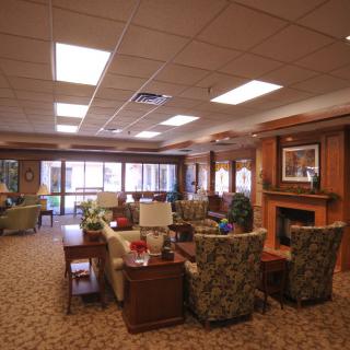 A comfortable lounge area with various seating arrangements, featuring a fireplace and large windows.