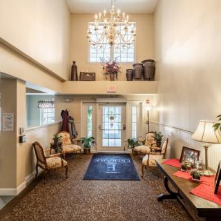 A well-decorated lobby with a large chandelier, elegant furniture, and natural light from the windows.