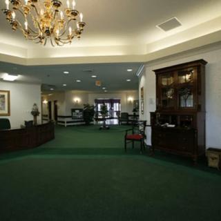 A spacious lobby with a green carpet, elegant furniture, and a chandelier.
