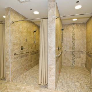 A modern, accessible shower area with tiled walls and curtains.