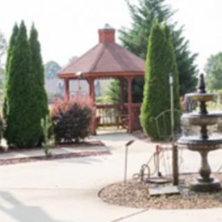A serene garden scene featuring a gazebo, fountain, and lush greenery.