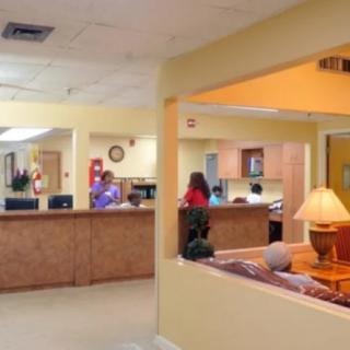 A hospital reception area with a waiting room and staff attending the front desk.
