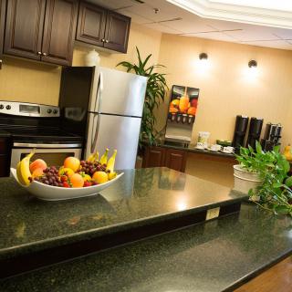A modern kitchen with stainless steel appliances, a fruit bowl on the countertop, and a coffee station in the background.