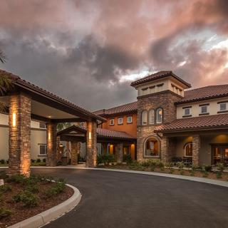 A beautifully designed building with a grand entrance and surrounding landscape under an evening sky.