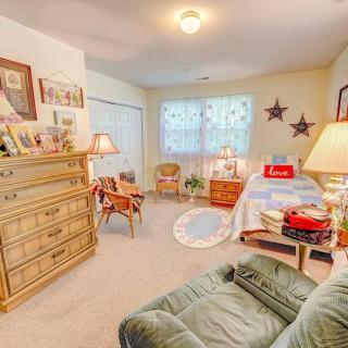 A cozy and well-decorated bedroom featuring a bed, dresser, chair, and warm lighting.