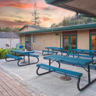 An outdoor patio with picnic tables under a vibrant sunset sky.