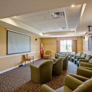 A conference room with comfortable seating and a projector screen.