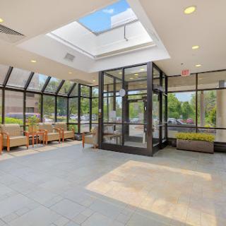 A bright and modern lobby featuring large glass walls and a skylight, creating an inviting atmosphere.