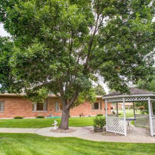 A well-maintained outdoor area featuring a large tree, a gazebo, and a brick building.