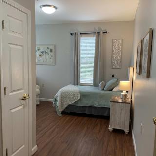 A cozy and well-decorated bedroom with a bed, nightstand, and lamp by the window.